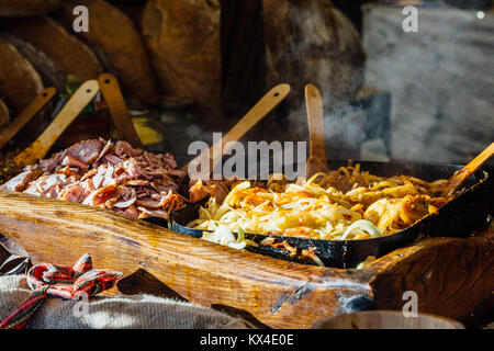 Cracovia mercatino di Natale in stallo che serve tradizionali delle fette di pane con grigliate di carne, cipolle e salsa. Foto Stock