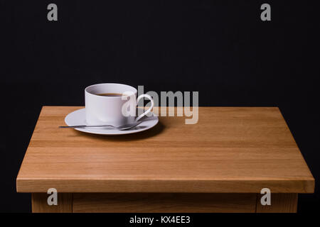 Una immagine di una tazza di caffè nero seduto su una quercia tavolo da caffè Foto Stock