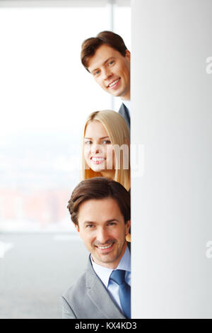 Happy business persone guardando fuori dall'angolo in office Foto Stock