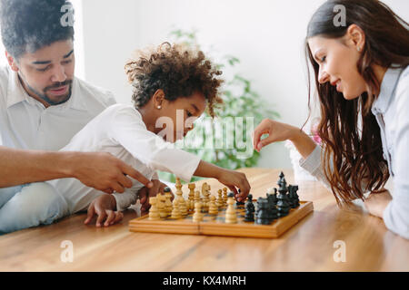 La famiglia felice giocando a scacchi insieme a casa Foto Stock