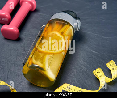 Bottiglia con agrumi rinfrescanti drink sulla roccia con manubri Foto Stock