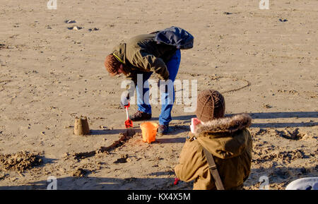 Weston-Super-Mare, Regno Unito. 07Th gen, 2018. Il 7 gennaio 2018. Una coppia giovane coraggioso il -5 C wind chill per fare castelli di sabbia sulla spiaggia di Weston. ©Alamy Live News/notizie JMF Credito: Signor Standfast/Alamy Live News Foto Stock