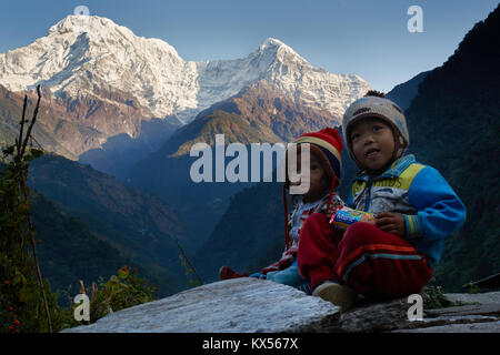 Bambini nepalesi di fronte Annapurna sud (Dakshin) e Hiunchuli, Annapurna massif, Nepal Foto Stock