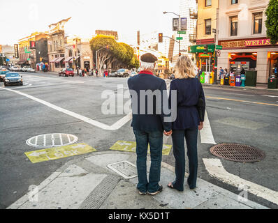 Due amanti mature tenendo le mani per le strade di San Francisco in prima serata, California, Stati Uniti d'America. Foto Stock