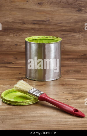 Vernice verde può con un pennello su un rustico sfondo di legno Foto Stock