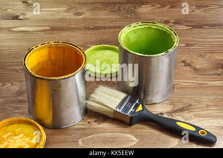 Verde e giallo barattoli di vernice con un pennello su un rustico sfondo di legno Foto Stock