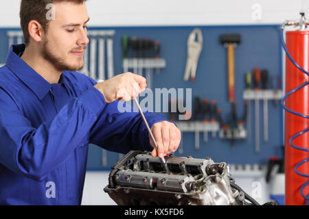 Soddisfatto meccanico la riparazione di un motore in moto in una officina meccanica Foto Stock