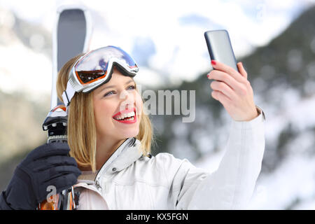 Ritratto di un buon sciatore prendendo un selfie con uno smartphone in un snowy montani Foto Stock