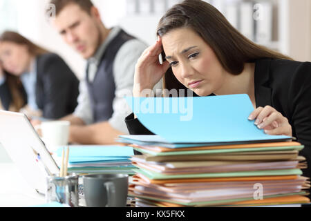 Preoccupato per il dipendente guardando un sacco di documenti in ufficio Foto Stock