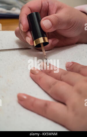 Una vista ravvicinata di una signora con le mani in mano come dipinge i suoi chiodi con smalto per unghie. Foto Stock