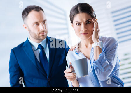 Bella donna di toccare la fronte tenendo una tazza di tè Foto Stock