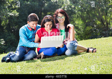 3 Indian giovani amici seduti insieme parco divertimento godendo Foto Stock