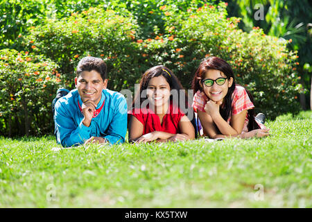 3 Indian College adolescenti amici Leggere Prenota giacente erba Park Foto Stock