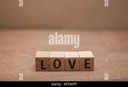 Lettere di legno formando la parola amore su sfondo marrone Foto Stock