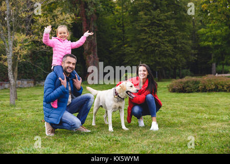 Felice giovani genitori con adorabile piccola figlia di cane e di divertirsi nel parco Foto Stock