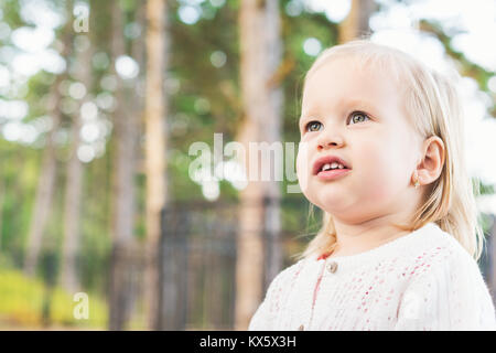 Immagine del dolce sovrappeso bambina guardando lontano dalla telecamera. Close up ritratto di un bambino. Simpatico bimbo con occhi verdi ritratto all'aperto. Foto Stock