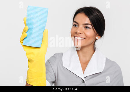 Close up ritratto di un felice gioiosa governante vestito in uniforme di pulizia con una spugna rimanendo isolate su sfondo bianco Foto Stock