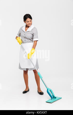 Lunghezza completa foto di felice governante in una pulitura uniforme piano con mop, isolati su sfondo bianco Foto Stock