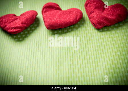 Colorati cuori di maglia su uno sfondo verde Foto Stock