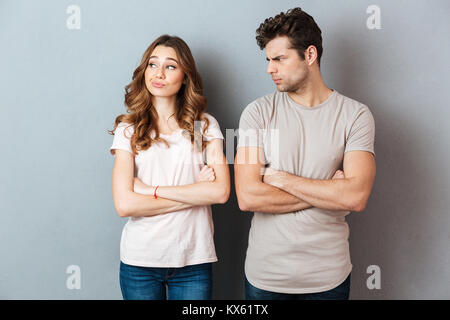 Deluso coppia giovane in piedi con le braccia incrociate sulla parete grigia Foto Stock