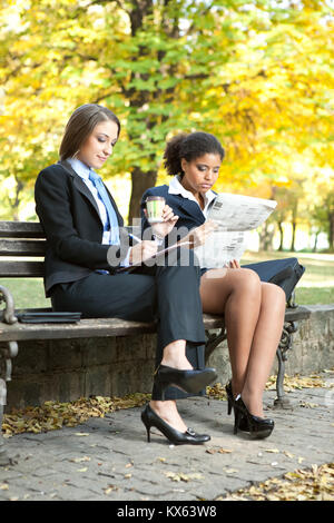 Colleghi di lavoro seduto sulla panchina nel parco, la gente di affari in pausa Foto Stock