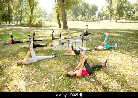 Un folto gruppo di persone che giace sull'erba e stretching, per esterno Foto Stock