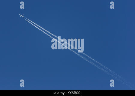 Piano lasciando un bianco contrail, attraversando la foto su un cielo blu- Foto Stock