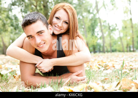 Giocoso coppia giovane in autunno park, sorridente e guardando la fotocamera Foto Stock