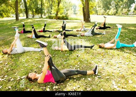 Gruppo stretching allenamento, grande gruppo si estende all'aperto su un prato verde in posizione di parcheggio Foto Stock