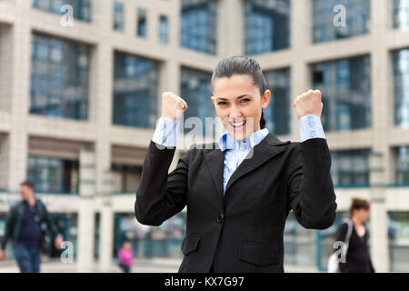 Imprenditrice estatica con le braccia sollevate nella parte anteriore di edifici per uffici Foto Stock