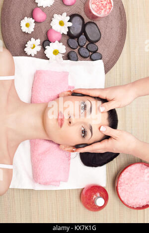 Giovane donna rilassata ricevere un massaggio della testa al centro termale Foto Stock