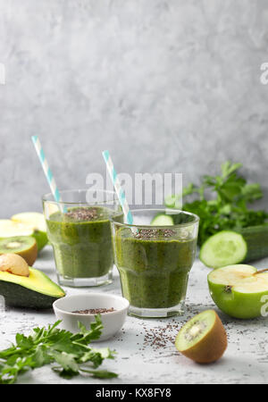 Green frullati in bicchieri, frutta e verdura fresche, erbe su un cemento grigio sfondo Foto Stock