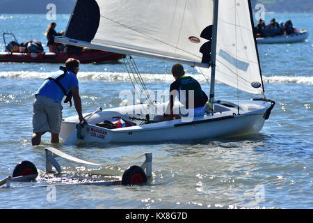 Il lancio di 420 classe dinghy a vela da rimorchio a mano in acqua poco profonda prima della gara. Foto Stock
