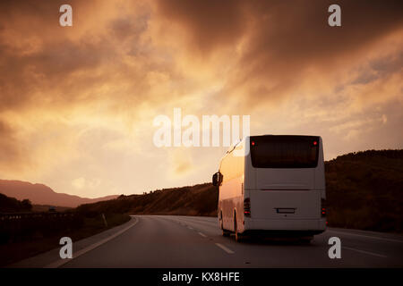 Bus bianco guida su strada con vista tramonto Foto Stock