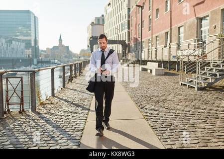 Giovane uomo d affari utilizza lo smartphone mentre si cammina home Foto Stock