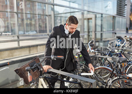 L'uomo come un " commuter " nella parte anteriore della sua moto al bike rack Foto Stock