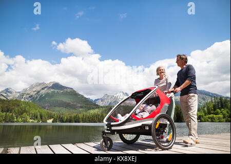 Coppia senior con i nipoti in jogging passeggino. Foto Stock