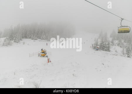 La gente lo sci e lo snowboard sul Skrzyczne mountain dopo la nevicata in una nebbiosa giornata invernale in Szczyrk ski resort in Polonia Foto Stock