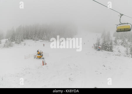 La gente lo sci e lo snowboard sul Skrzyczne mountain dopo la nevicata in una nebbiosa giornata invernale in Szczyrk ski resort in Polonia Foto Stock