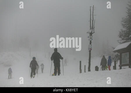 Gli sciatori e gli snowboarder escursionisti che arrivano al coperto di neve e nebbia vertice di Skrzyczne mountain in Szczyrk voce per le piste da sci e sentieri escursionistici Foto Stock