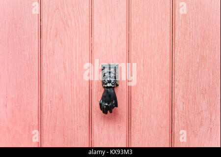 Vista frontale di un nero a mano a forma di porta-respingente montato su un vecchio rosa porta anteriore. Foto Stock