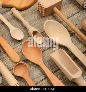 Set di utensili da cucina su un tavolo di legno. Cucchiaio e forchetta, perno di rotolamento, il martello di cucina, spatola. Vista dall'alto. Foto Stock