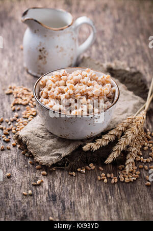 Ciotola di porridge di orzo su sfondo di legno Foto Stock