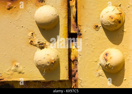 Texture astratte e forme: Invecchiamento metallo e bulloni su un pezzo di invecchiamento dei macchinari. Completare con la formazione di ruggine e la formazione di bolle, corrosione di vernice gialla. Foto Stock