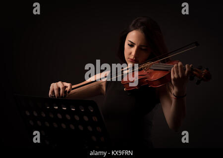 Bella giovane donna riproduzione di un violino su sfondo nero Foto Stock