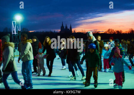 Praga, Repubblica Ceca - Gennaio 06, 2018: Pattinatori pattinaggio su un pubblico pista di pattinaggio su ghiaccio con uno sfondo del Castello di Praga in Letna Park Foto Stock