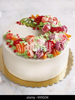 Festosa torta con crema di fiori e di frutti su uno sfondo luminoso Foto Stock