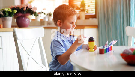 Carino piccolo ragazzo di pittura delle uova di pasqua Foto Stock