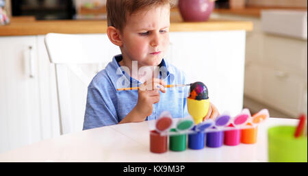 Carino piccolo ragazzo di pittura delle uova di pasqua Foto Stock