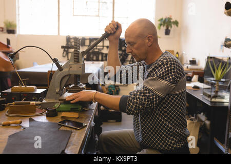 Sarto lavorando su strumenti vintage premendo i pulsanti sul cuoio Foto Stock